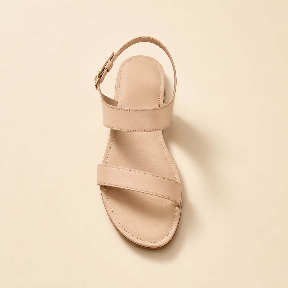 Ankle Strap Flat, photographed from above against a sand-beige background