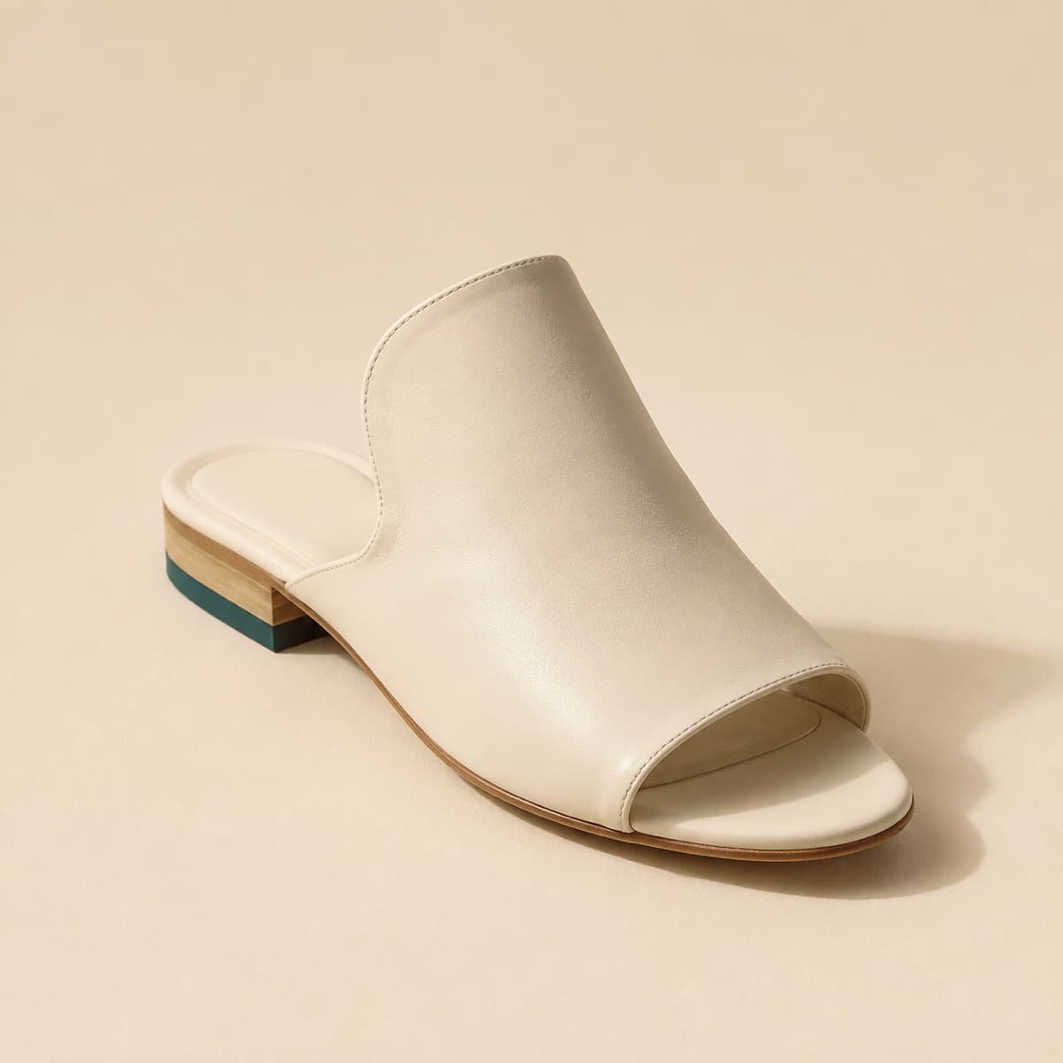 Mule High Instep, photographed from above against a sand-beige background