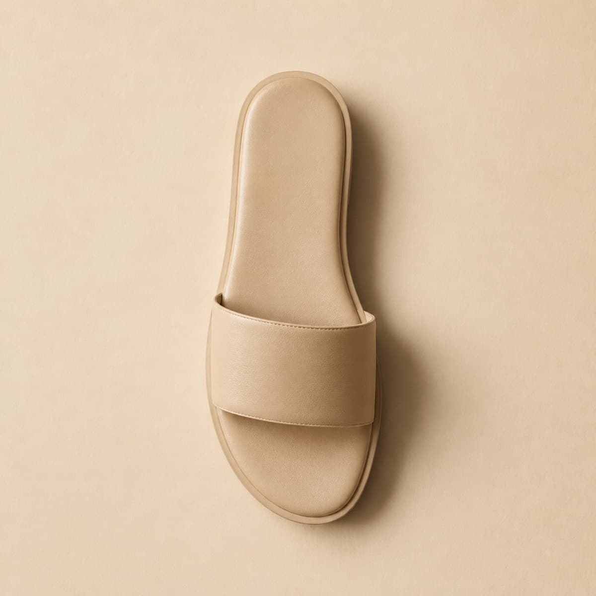 Slide Leather, photographed from above against a sand-beige background
